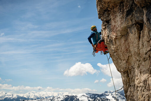 Ein Kletterer der sich gerade neu sichern möchte vor einem schönen blauen Himmel.
